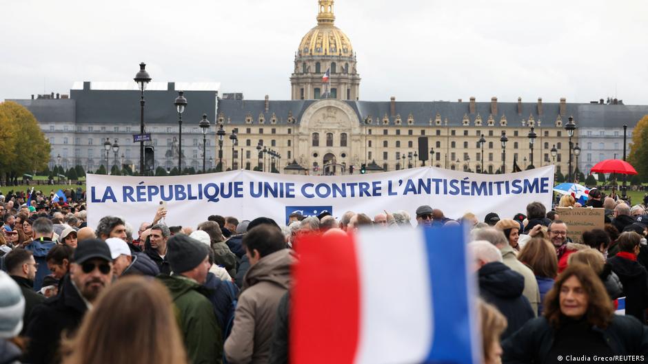 مظاهرة حاشدة في باريس ضد تزايد جرائم معاداة السامية. صورة من: Claudia Greco/REUTERS Thousands of people stand in a public square. Someone holds up a French flag and in the background, people hold a banner saying: "The Republic united against anti-Semitism"