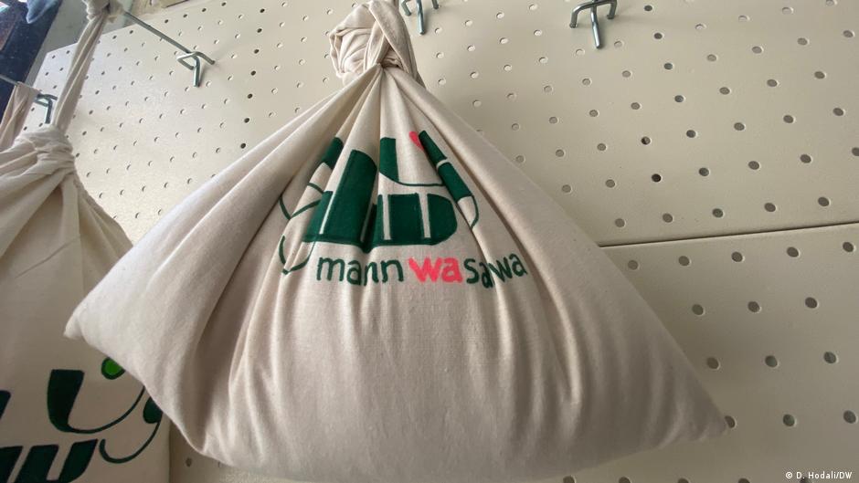 المن والسلوى - مشروع ضد ارتفاع الأسعار والطائفية السياسية في لبنان. Cotton shopping bags bearing the name of the Mann wa Salwa store hang from hooks on a wall Bild Diana Hodali/DW