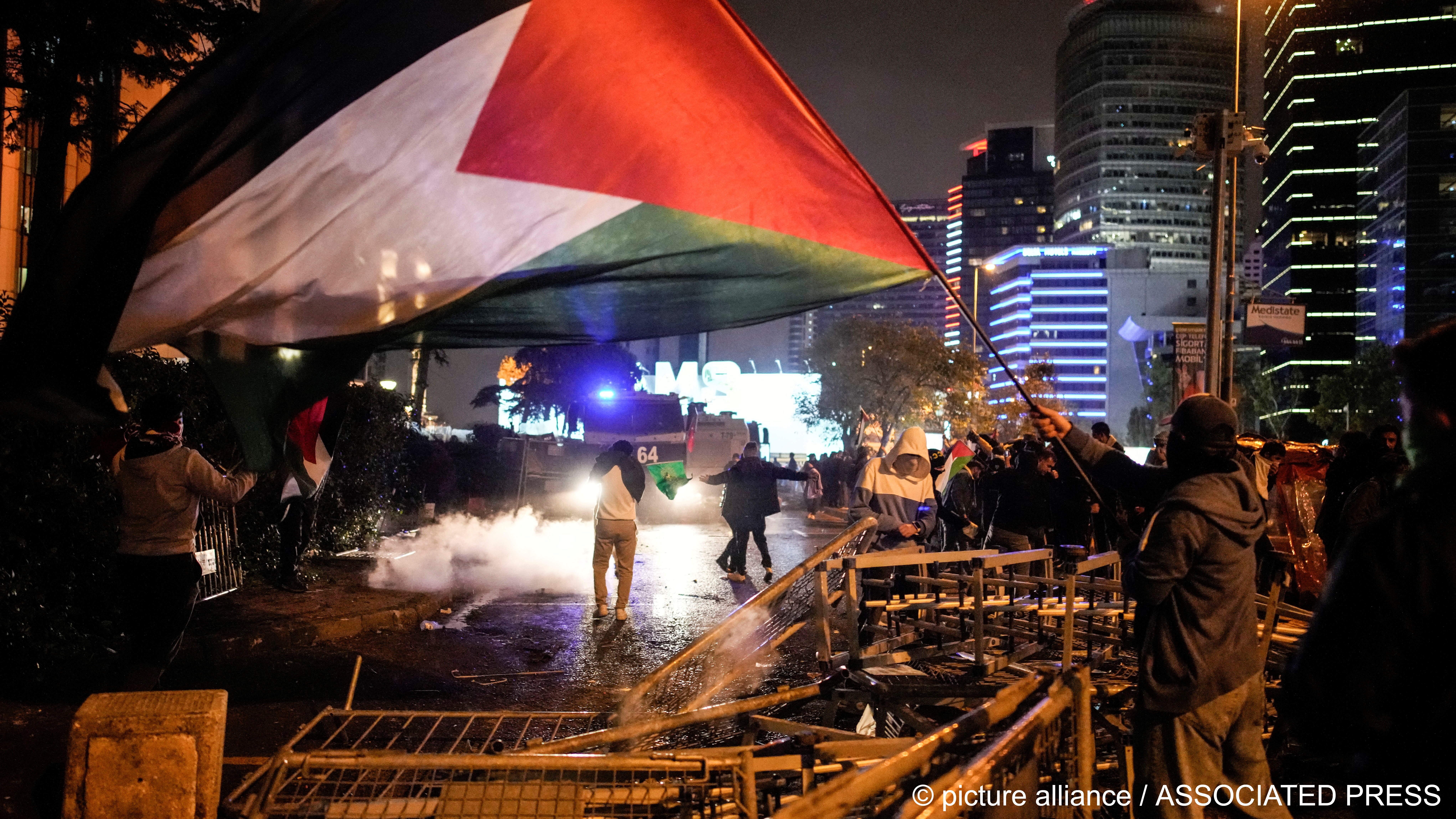 A man waves a Palestinian flag and others clash with anti riot policemen outside the Israeli consulate during a protest to show solidarity with Palestinians, Istanbul, Turkey, 18 October 2023