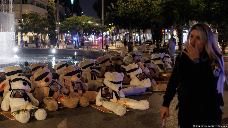 Soft teddy bears with their eyes covered and showing signs of injury are displayed on a Tel Aviv street