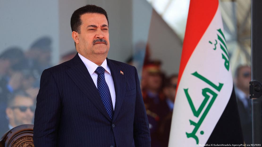 رئيس الوزراء العراقي محمد شياع السوداني. صورة من: Murtadha Al-Sudani/Anadolu Agency/Pool via REUTERS Iraqi Prime Minister Mohammed Shia al-Sudani stands next to the Iraqi flag at an event in Baghdad