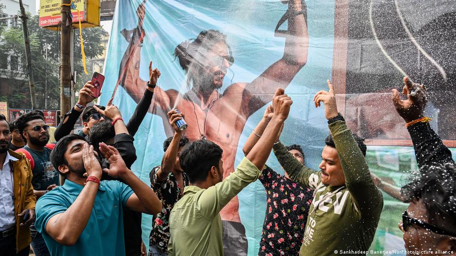 Large format poster of Bollywood star Shah Rukh Khan in his latest film "Dunki"; in the foreground his fans celebrate