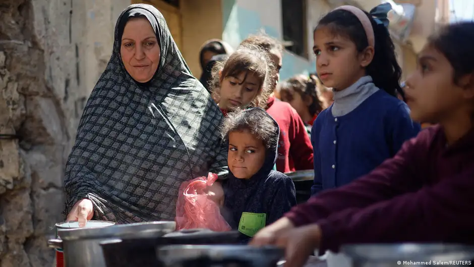 A woman and several children line up for food at a charity kitchen in Rafah, Gaza, 5 March 2024