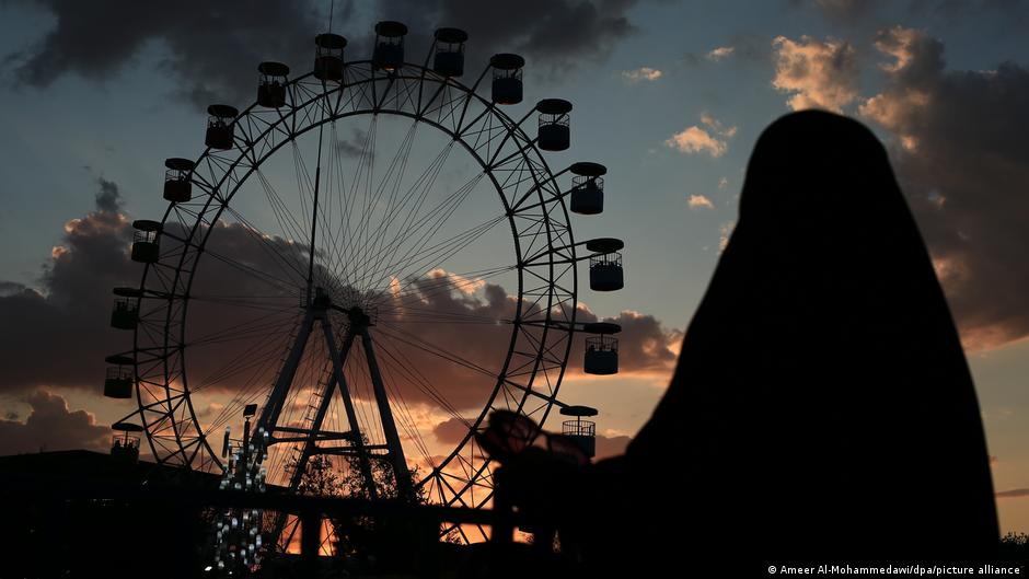 A woman watches a ferris wheel in an amusement park in Baghdad, Iraq.