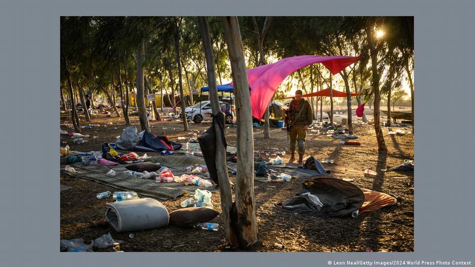 An Israeli soldier stands in a forested clearing and looks down at the ground that is covered in debris following the Hamas attack on Israel