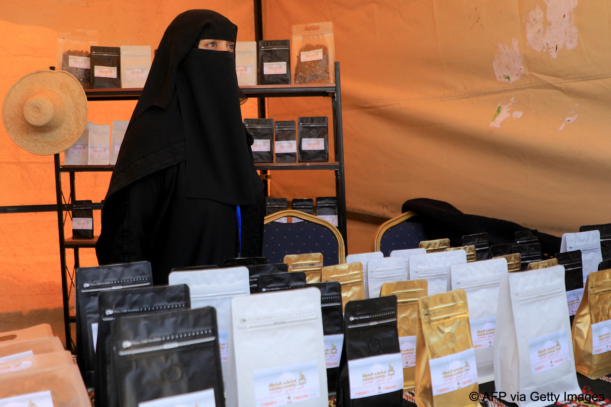 A woman wearing a black hijab and face veil displays products at a fair organised to promote locally grown coffee in Sanaa, Yemen, 3 March 2024