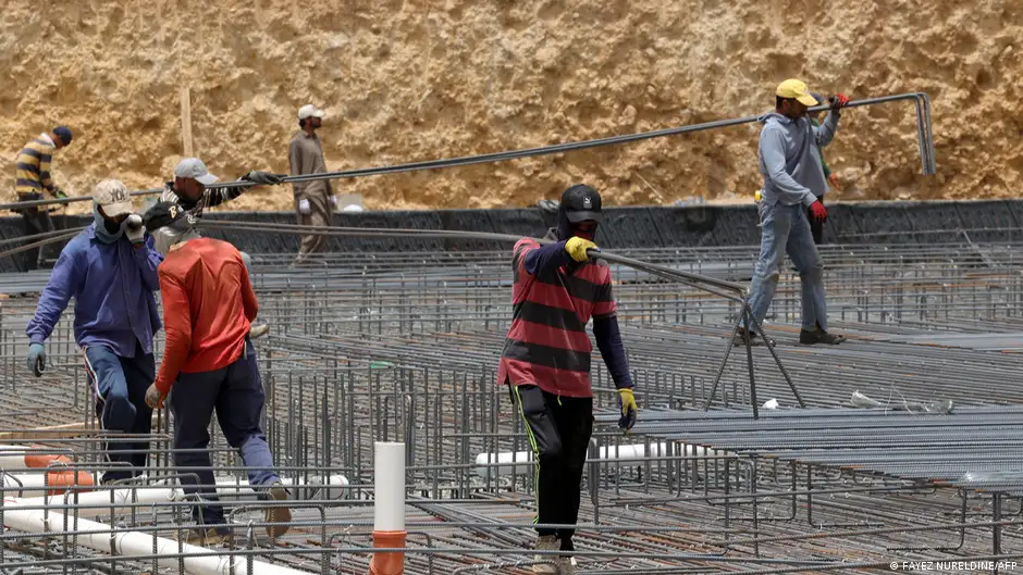 Workers carry metal bars on a construction site in Riyadh