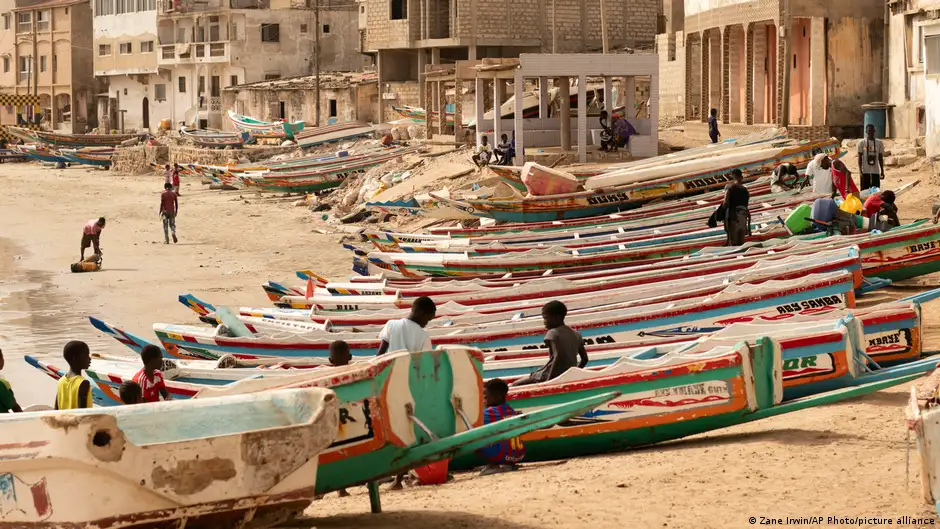 Children can be seen in between colourful boats lined up on a beach in Dakar, Senegal