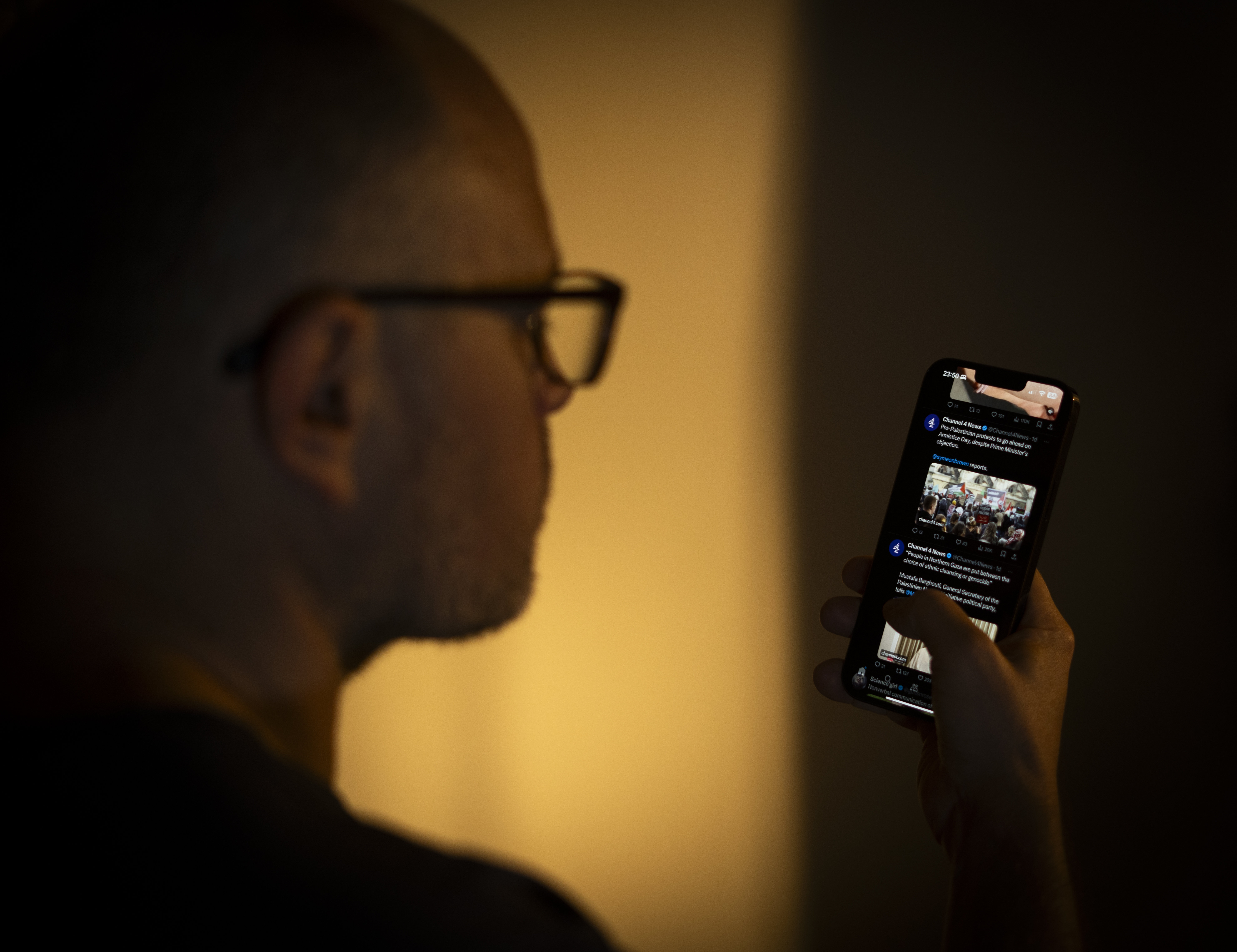 The photo illustration shows a user scrolling through his news feed on platform X on his smartphone.