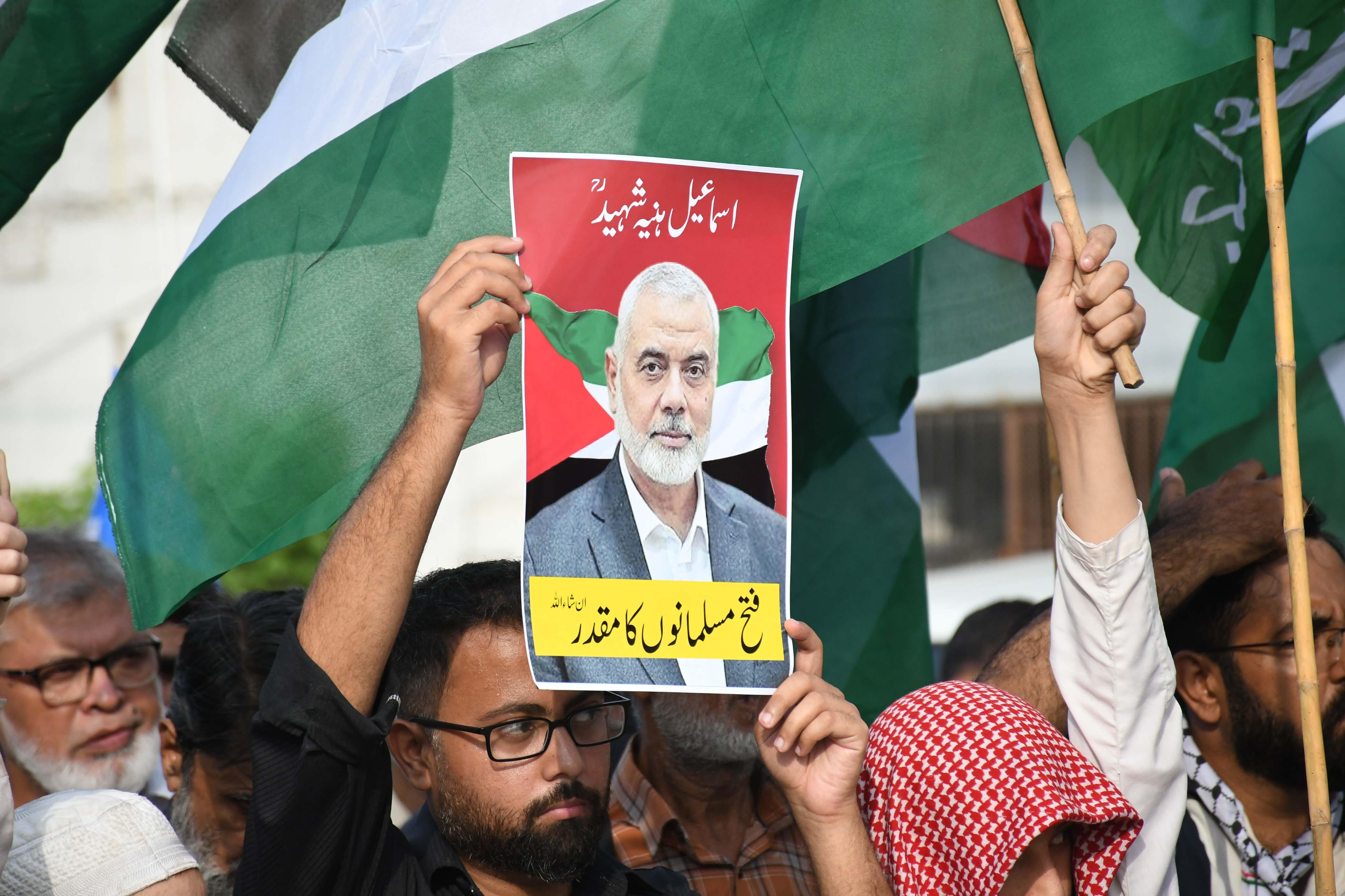 A man at a Palestine solidarity demo in Pakistan holds up a printed image of assassinated Hamas leader Ismail Haniyeh.