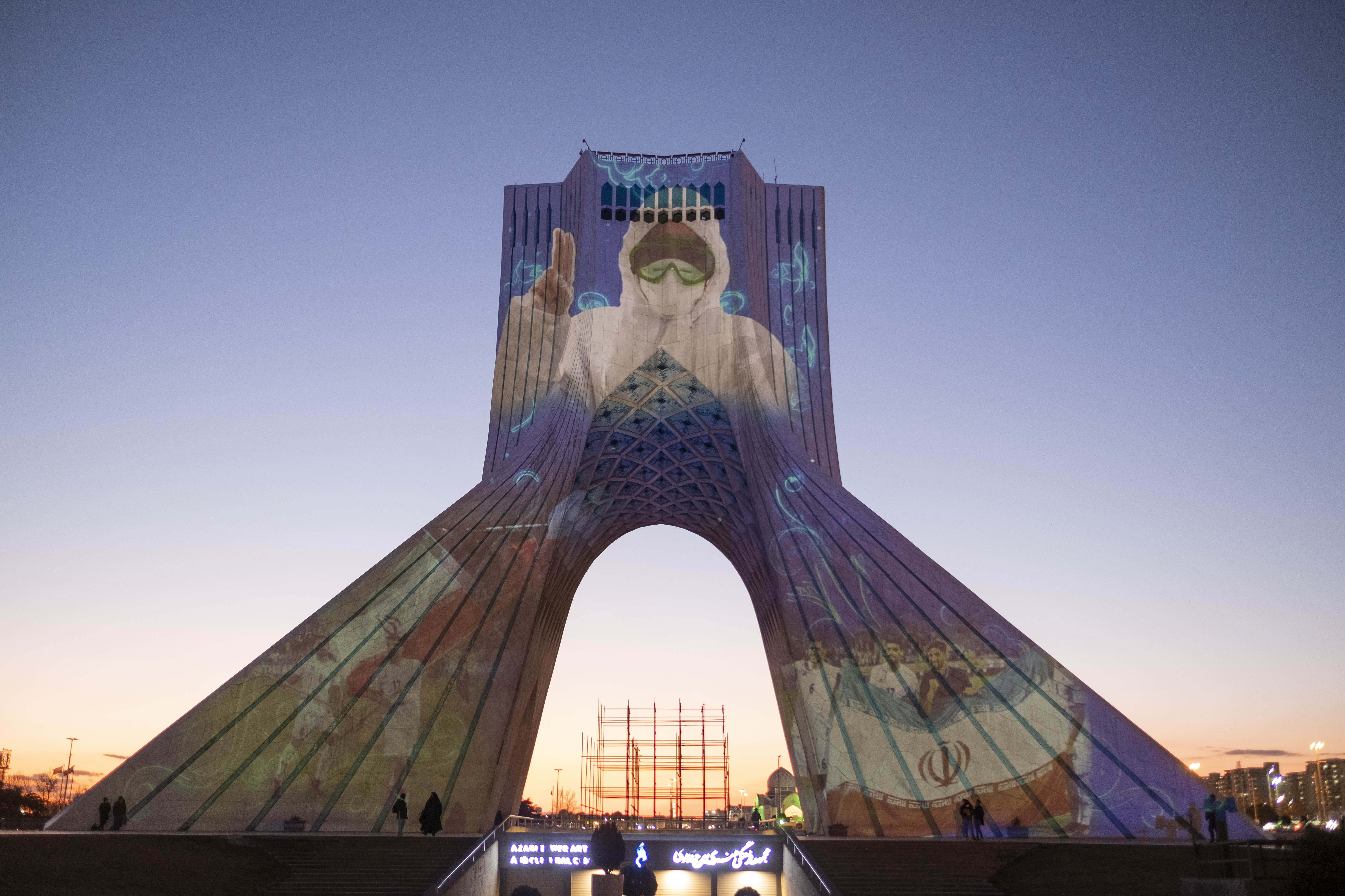 The portrait of a nurse in a protective suit is projected onto the Azadi monument in Tehran.