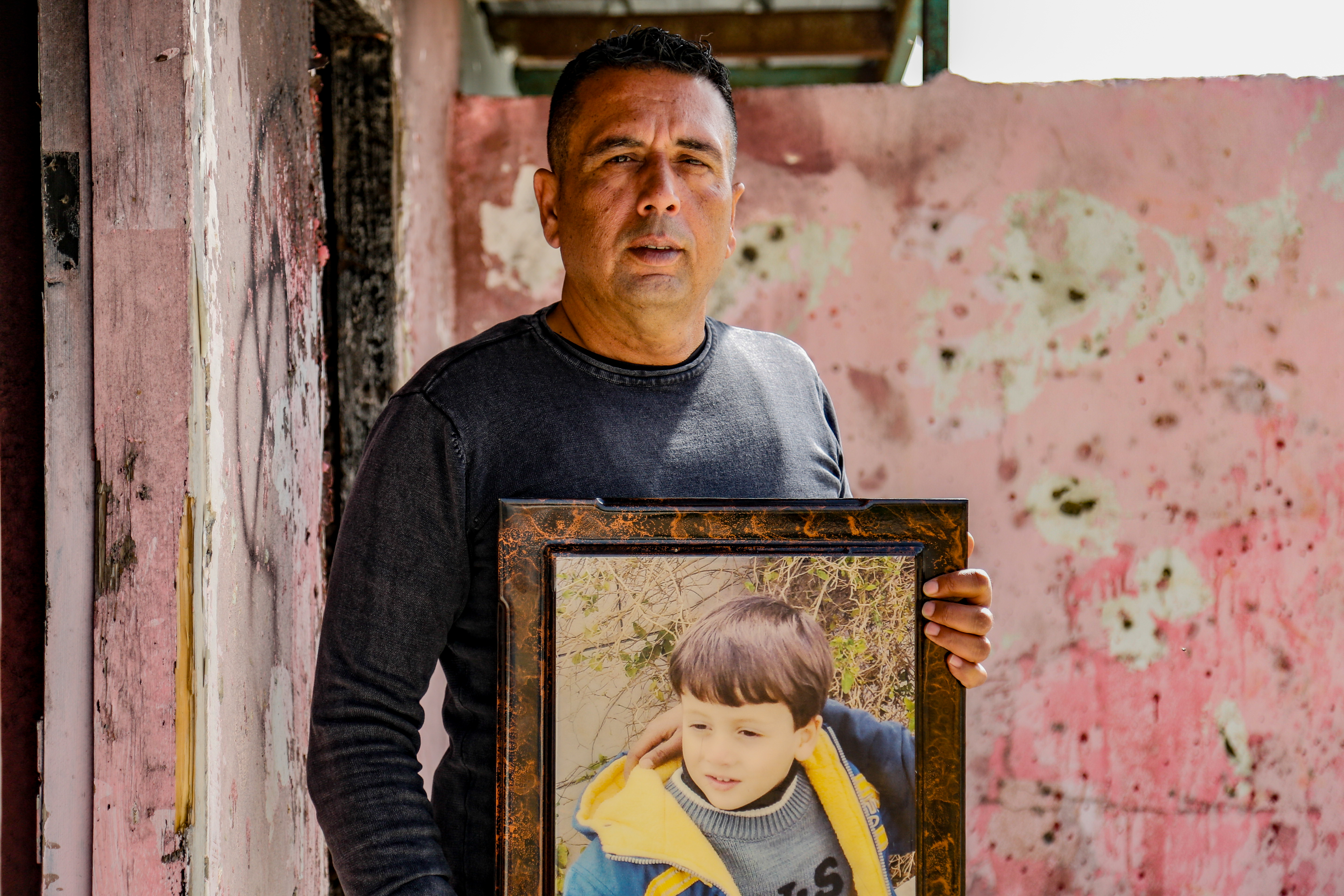 Die Hauptfigur des Buches hält ein Foto seines Sohnes vor dem Hintergrund eines rosafarbenen Gebäudes