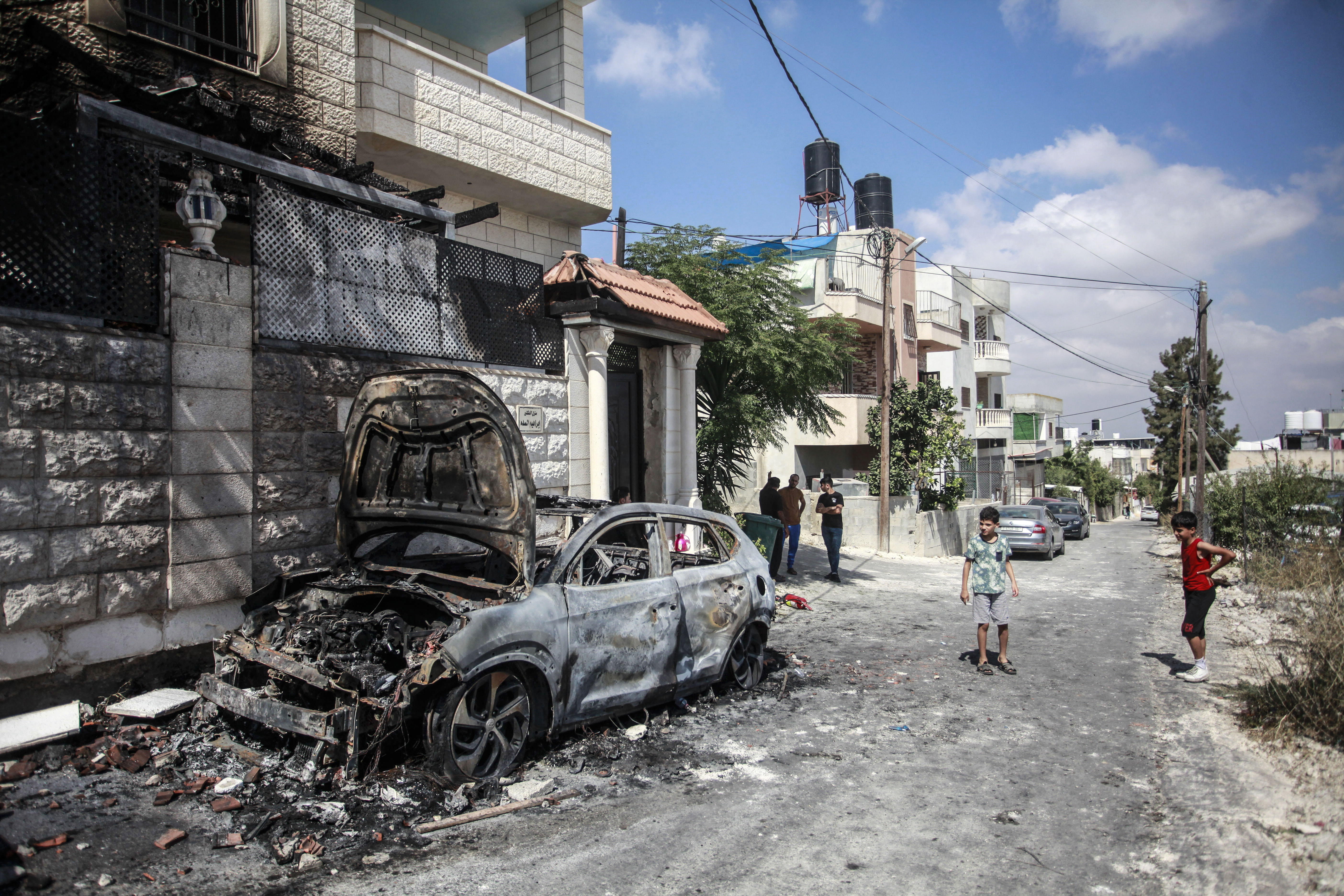 A group of children inspect the ruins of a burnt out car parked on a street in Jit in the West Bank.