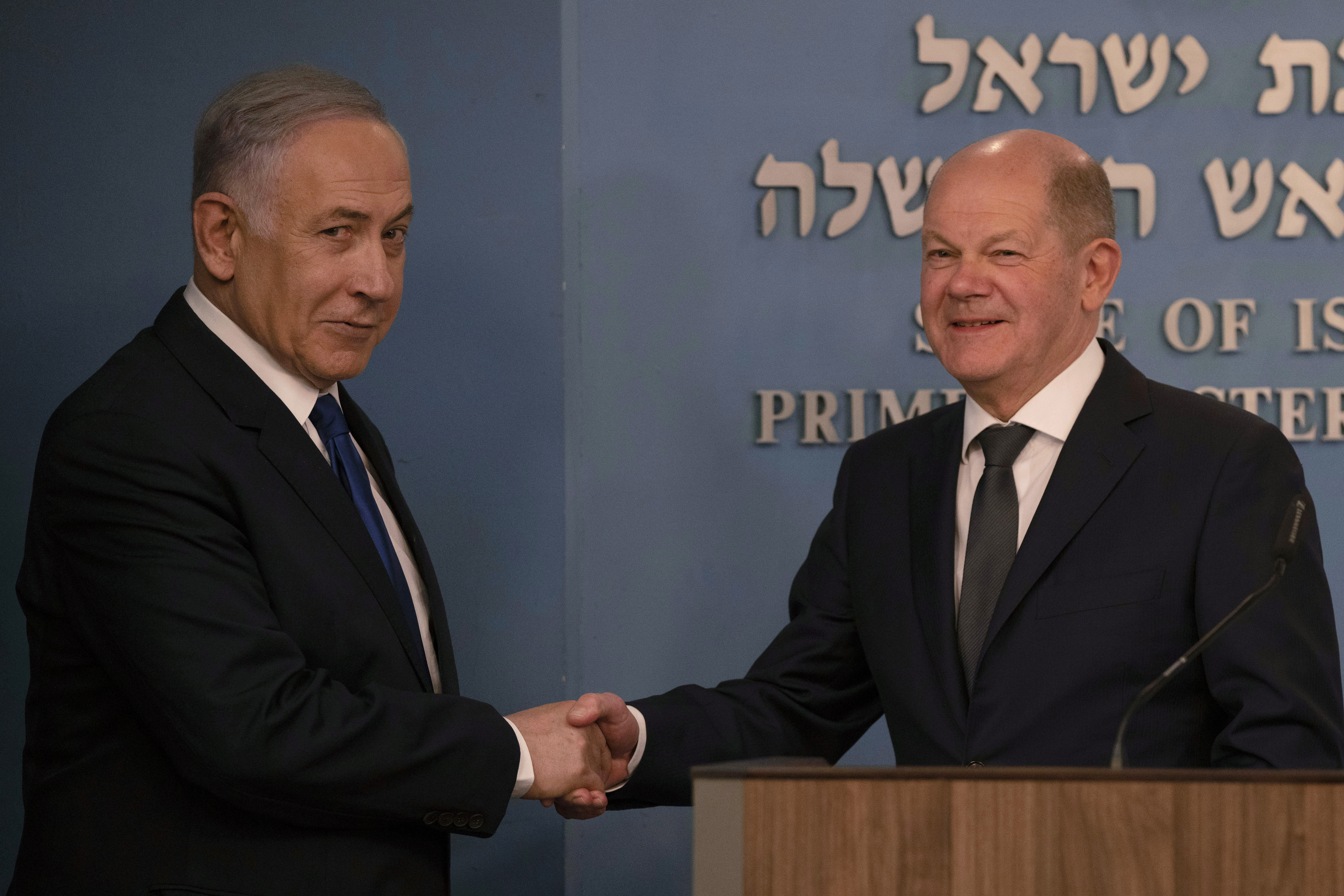 Netanyahu and Olaf Scholz shake hands.