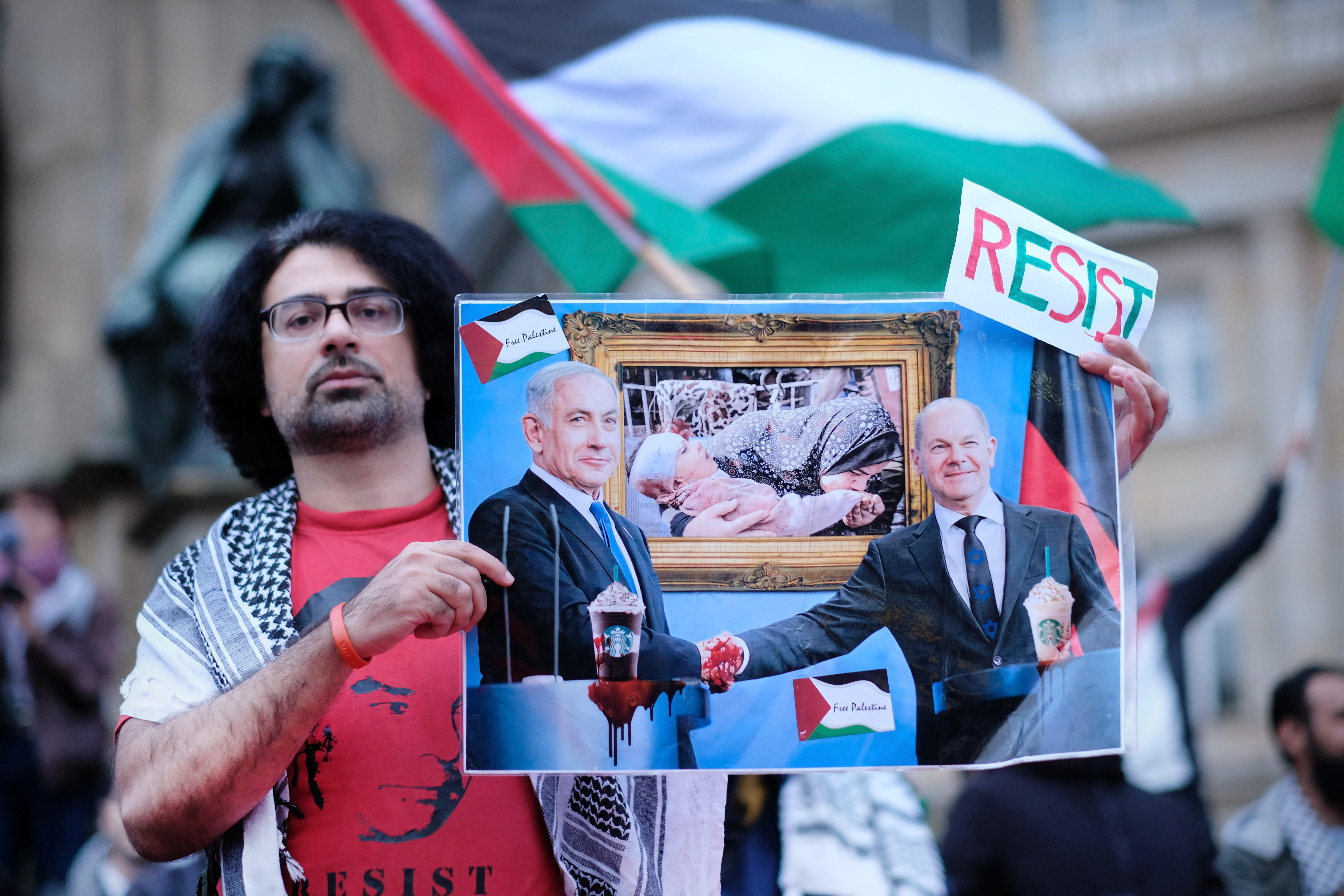 Demonstrator holds a caricature of Netanyahu and Scholz in his hand