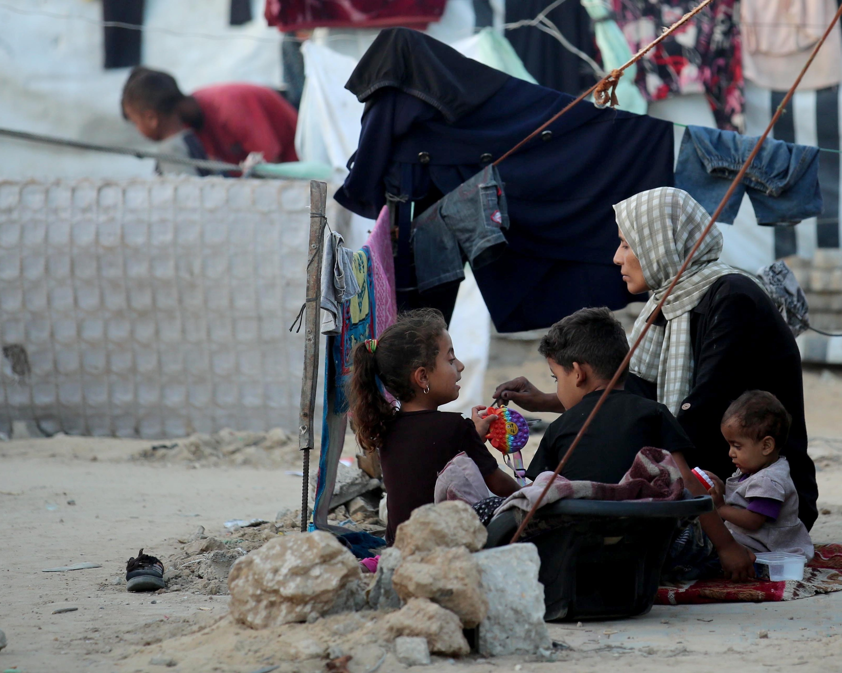 Eine Mutter sitzt mit ihre Kinder in einem Flüchtlingslager in Gaza