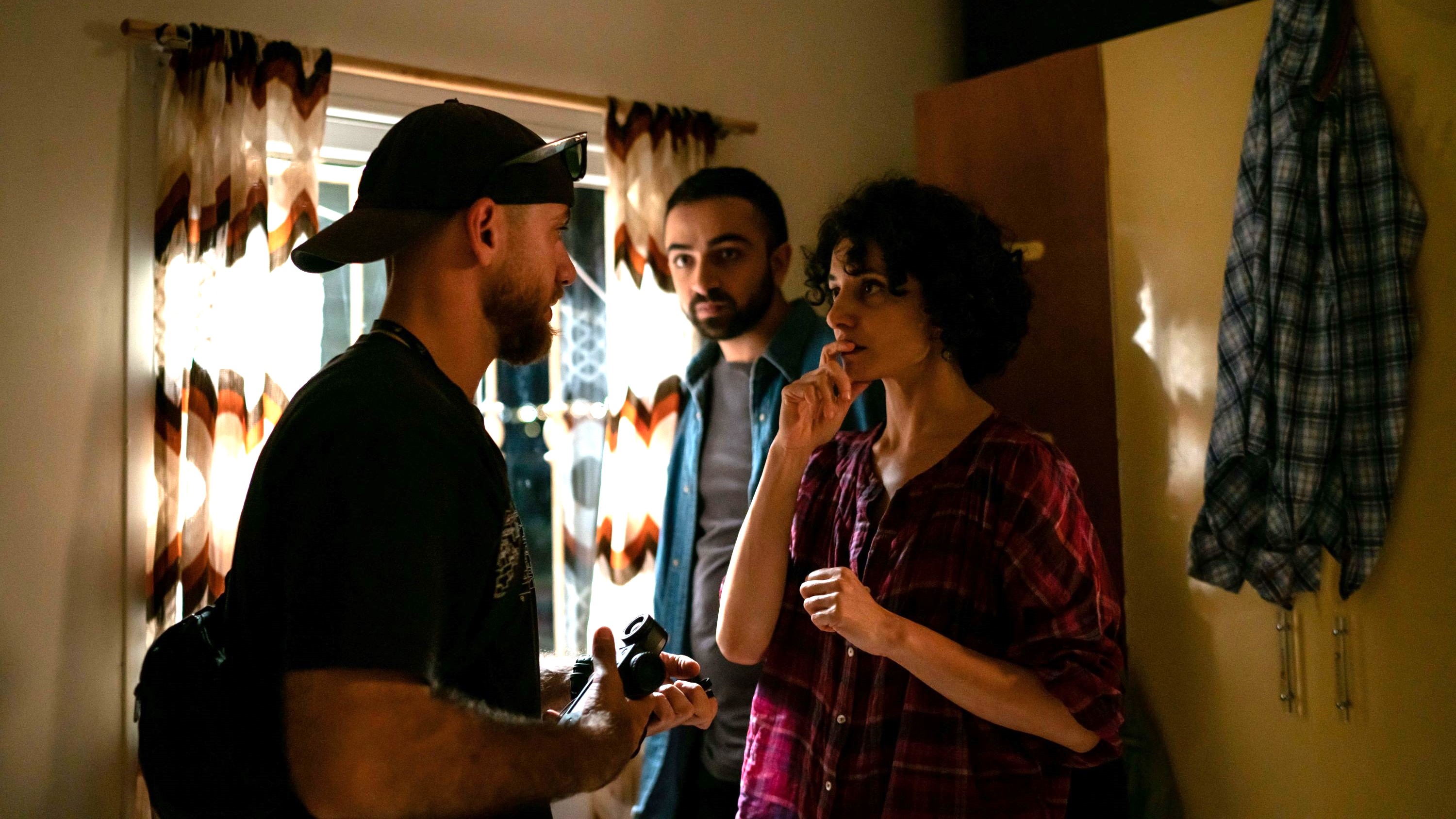 Two men and a woman stand in a room and talk to each other