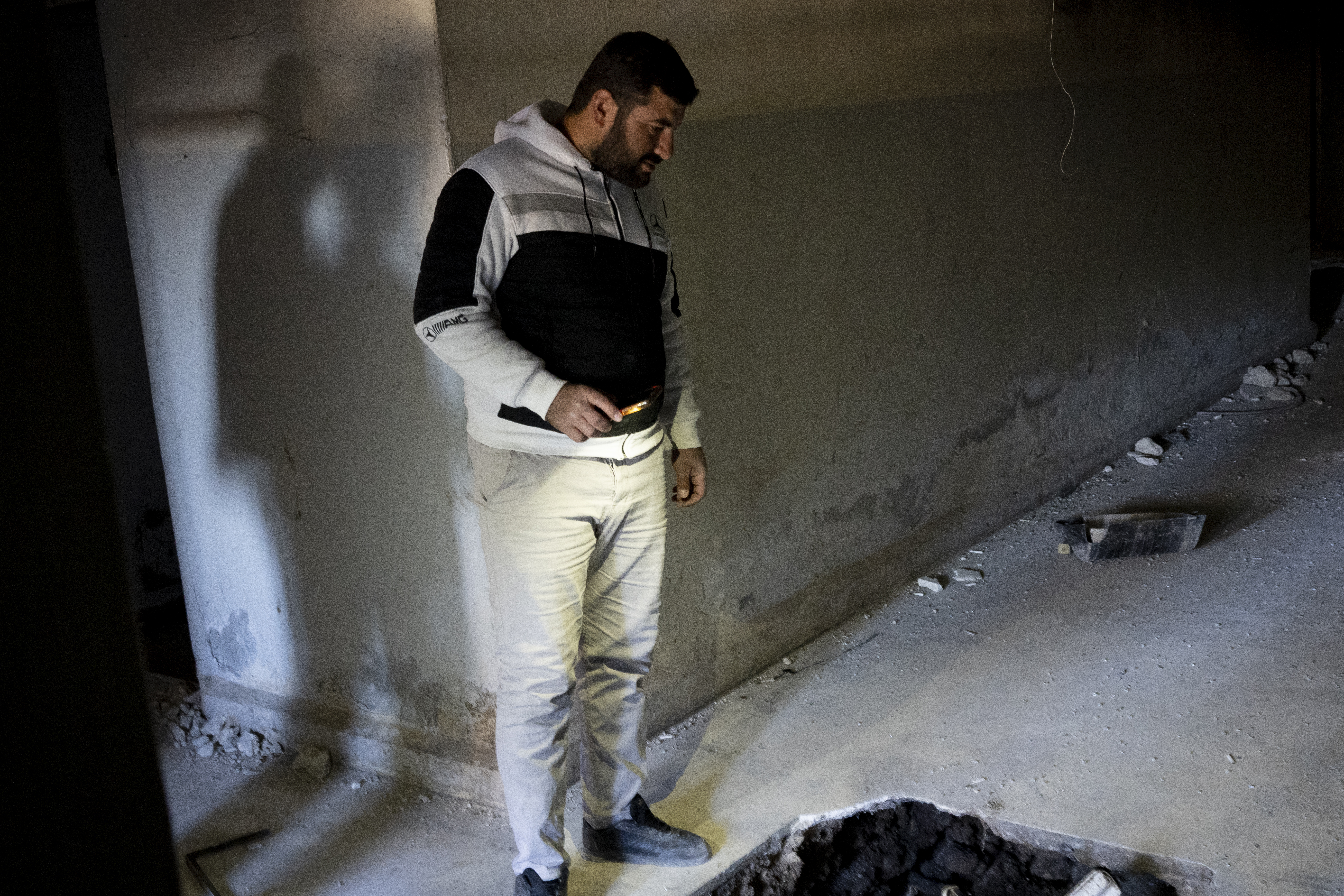 A man stands alone in a corridor of an abandoned building.