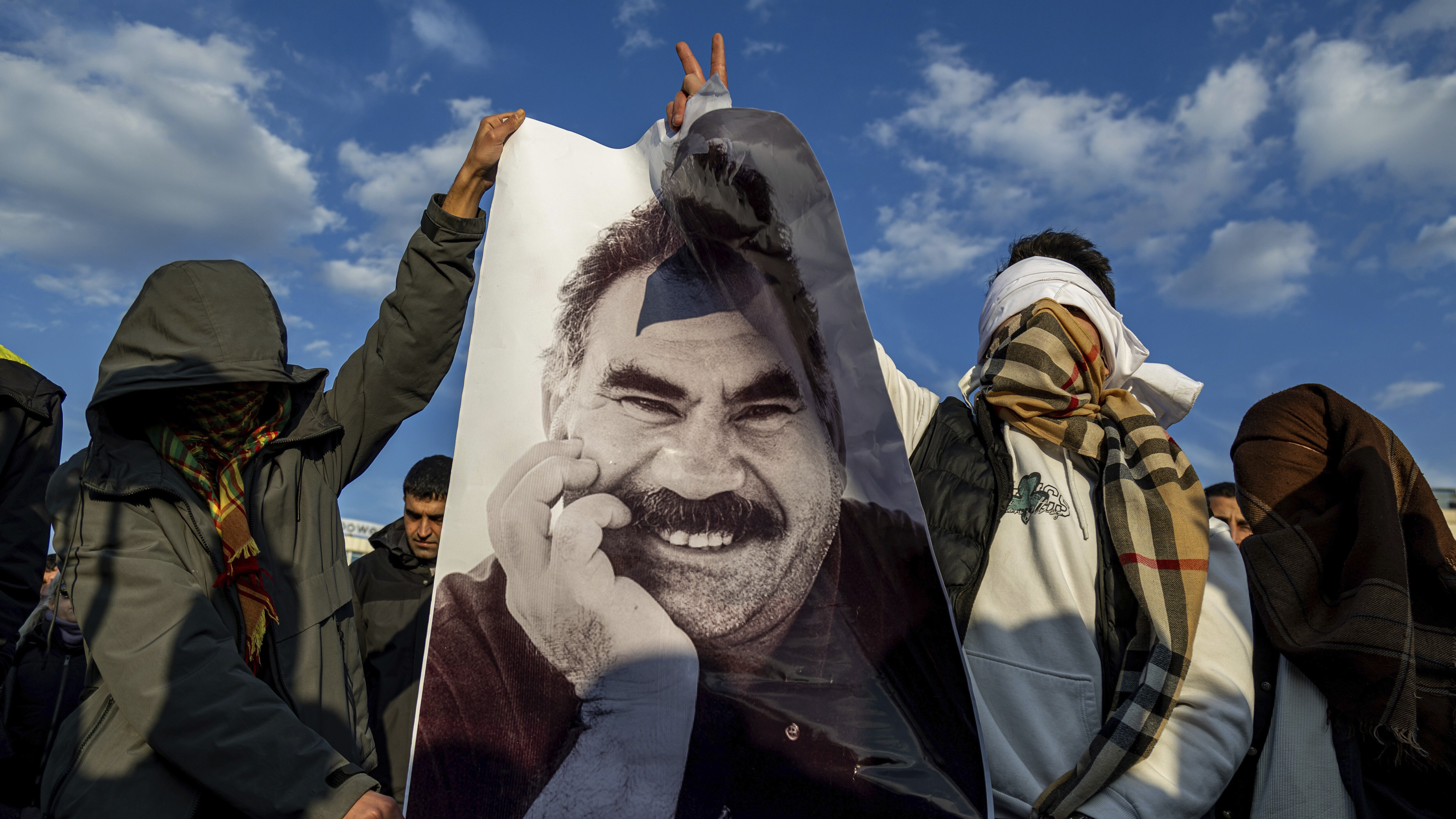 Two hidden youngsters hold poster with face of a smiling man 