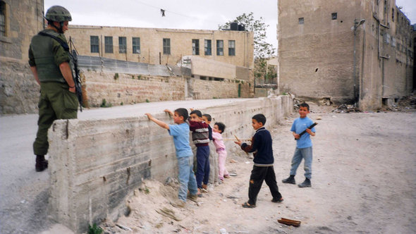 Ausstellungsexponat - Palästinensische Kinder spielen eine Checkpoint-Kontrolle vor einem israelischen Soldaten der IDF; Foto: © Breaking the Silence