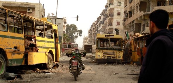 An opposition fighter crosses an area under attack by snipers from the government forces on his motorcycle in the front line of the Bustan al-Basha district of Aleppo (photo: AFP)