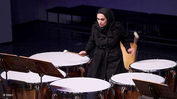 A young woman playing the tympani in an orchestra