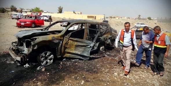 Irakische Rettungskräfte neben den Überresten eines Autobombenanschlags in Kirkuk, September 2012; Foto: EPA/Khalil Al-A'nei/dapd)