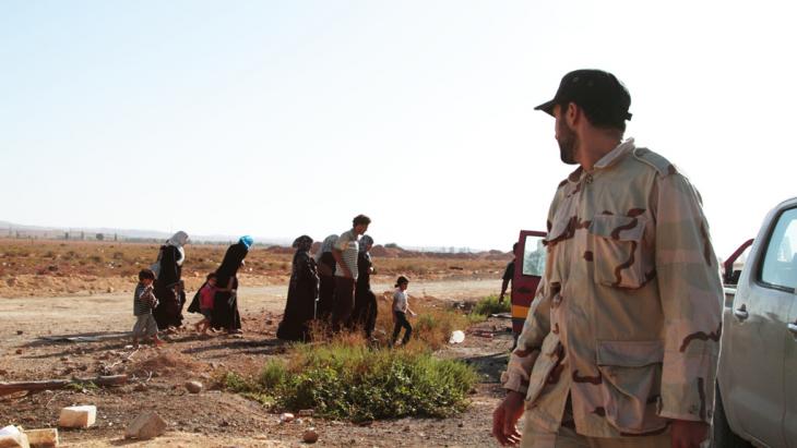 Security official and a refugee family in Libya (photo: Gaia Anderson/DW)