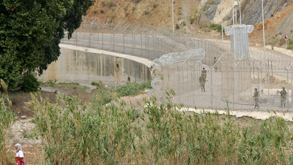 A Moroccan woman walks past the razor wired fence separating Morocco and Spain's North African enclave of Ceuta on the Moroccan border (photo: picture alliance/AP Images)