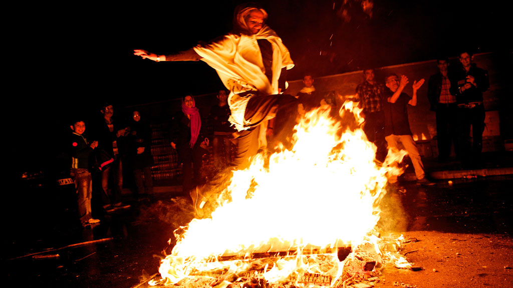 Eine Frau springt im Rahmen der Chaharshanbeh-Soori-Festlichkeit über eine Flamme; Foto: Behrouz Mehri/AFP/Getty Images