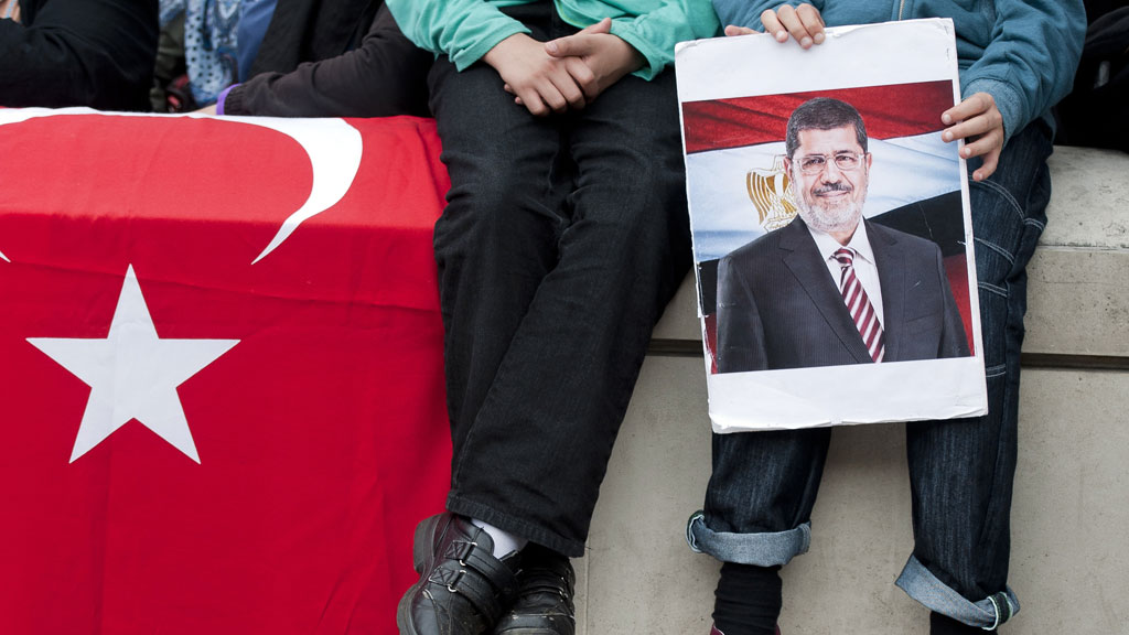 A young demonstrator holds a picture of ousted Egyptian President Mohamed Morsi during a protest in support of the Muslim Brotherhood outside 10 Downing Street, London, on 18 August 2013 (photo: WILL OLIVER/AFP/Getty Images)