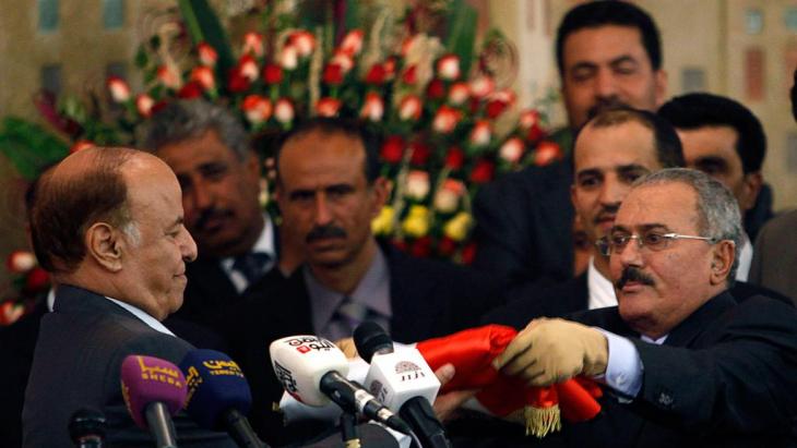 Yemeni President Abd-Rabbu Mansour Hadi (left) is handed the Yemeni flag by Ali Abdullah Saleh in Sanaa on 27 February 2012 (photo: Reuters)