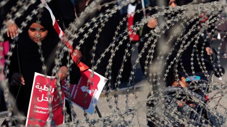 Demonstrators hold up placards that read "Democracy is the solution" during a demonstation that was blocked off by security forces in Manama (photo: dpa/picture-alliance)