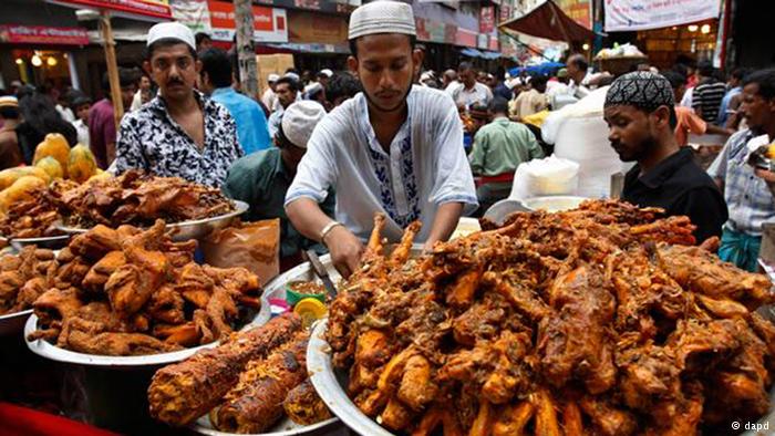 Stallholders and plates loaded with cooked meat at a market in Dhaka. Photo: dapd