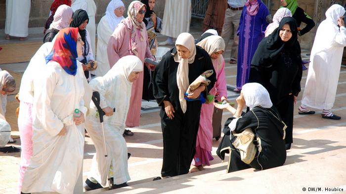 Four women giving alms to another woman sitting on the street in Morocco. Photo: DW/M. Houbice