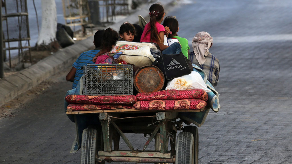 Palestinians flee their homes on a horse-drawn carriage to seek shelter in Gaza City, 13 July 2014. Photo: EPA/MOHAMMED SABER