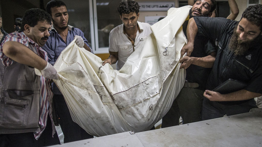 Palestinian volunteers at al-Shifa hospital in Gaza lift a body bag (photo: Marco Longari/AFP/Getty Images)