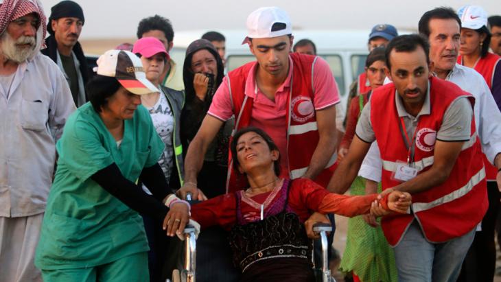 Members of the Kurdish Red Crescent helping a Yazidi woman (photo: Reuters)