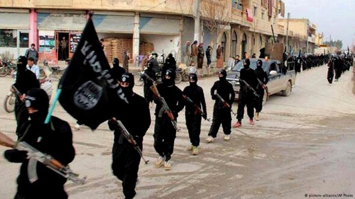 Members of IS terror militias marching down a street in Iraq (photo: picture-alliance/AP)