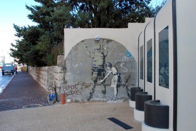 An Israeli soldier being frisked by a young girl, Bethlehem, 2007 (photo: Laura Overmeyer)