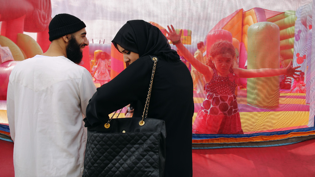 A family watch their children on a bouncy castle during an Eid celebration  in Burgess Park on July 28, 2014 in London, England (photo: Getty Images/D. Kitwood)