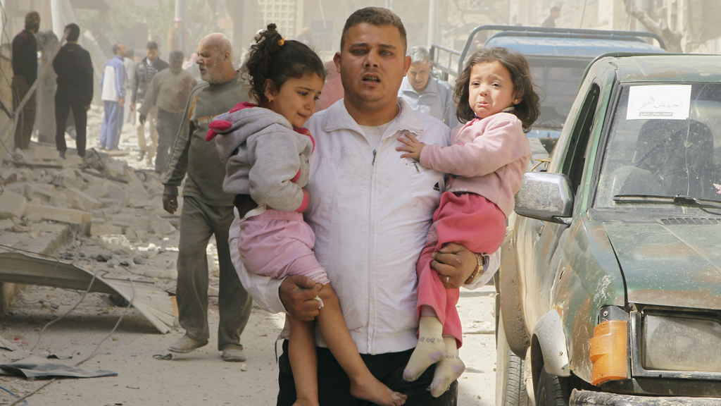 Nach einem Fassbombenabwurf von Kampfjets des Regimes auf ein Wohnviertel in Idlib rettet ein Mann zwei traumatisierte Kinder aus den Trümmern der Häuser; Foto: Reuters/Ammar Abdullah