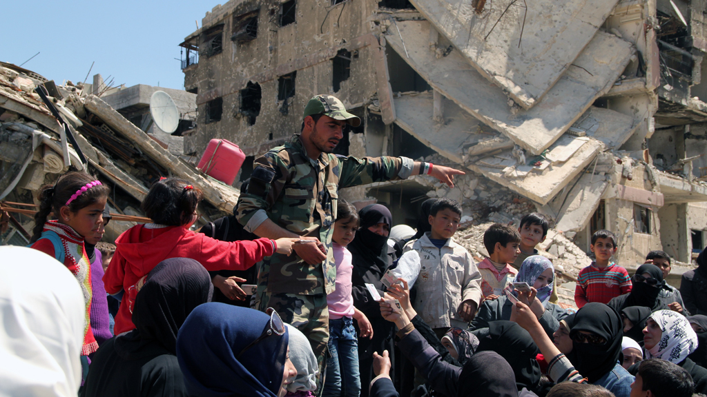 Residents of the Yarmouk refugee camp show their documents to a serviceman in order to leave a dangerous zone (photo: picture-alliance/dpa)