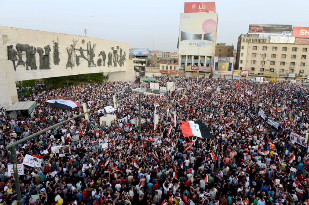 ساحة التحرير، هي الميدان الرئيسي في مركز بغداد، وفي الصورة حشود مؤلفة من المتظاهرين تحت جدارية نصب الحرية للفنان العراقي الراحل جواد سليم. ويمكن ملاحظة قدم المباني المحيطة بالمكان وتهالكها بعد ان غابت مظاهر الاعمار والاصلاح والصيانة والعمران عن المدينة منذ 12 عاما. 