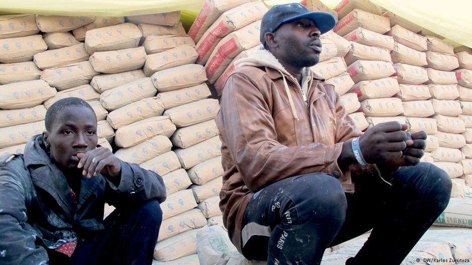 Men crouch on a street in Zuwara, waiting for occasional work