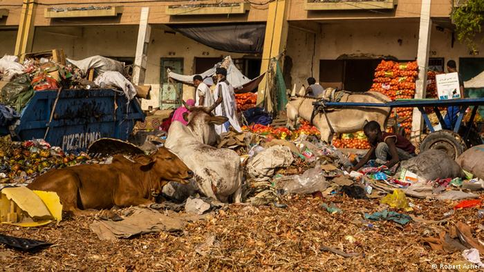 A boy sits in rubbish along the side of the road