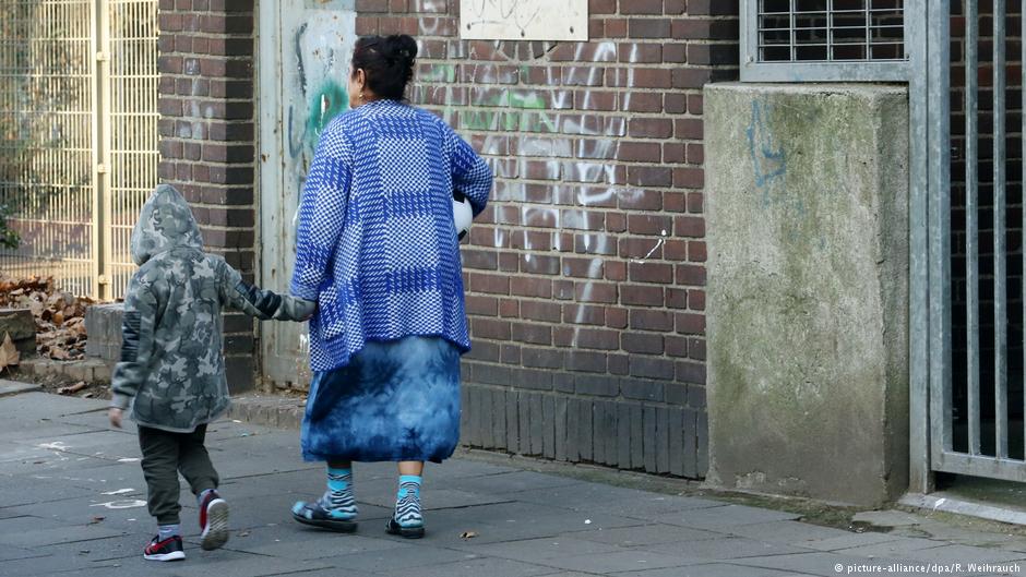 A woman and child walk past a house earmarked for demolition in Duisburg-Marxloh, 20.12.2016 (photo: Roland Weihrauch/dpa)