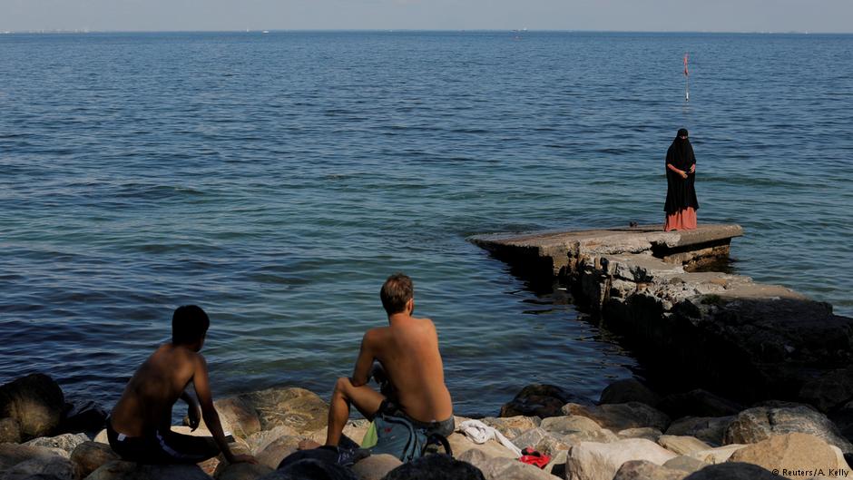 Swimmers look on as Anna-Bella, 26, who was born in Peru and converted to Islam at age 20, walks along the seafront in Copenhagen, Denmark, 24 July 2018 (photo: Reuters/Andrew Kelly)