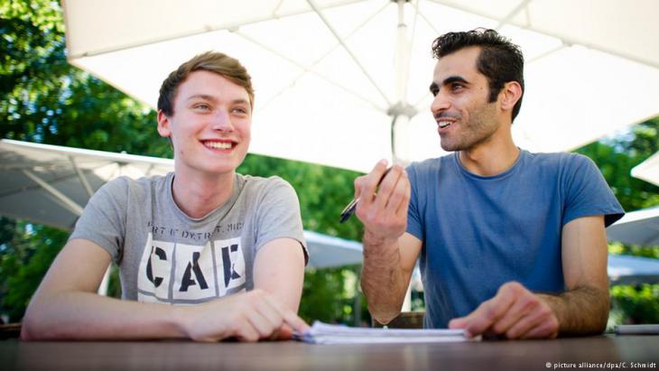 Der deutsche Student Tim Schwarz (links) hilft dem syrischen Flüchtling Renas Ottmann (rechts) beim Erlernen der deutschen Sprache auf dem Gelände der Goethe-Universität in Frankfurt am Main (Foto: picture alliance/dpa/C. Schmidt).