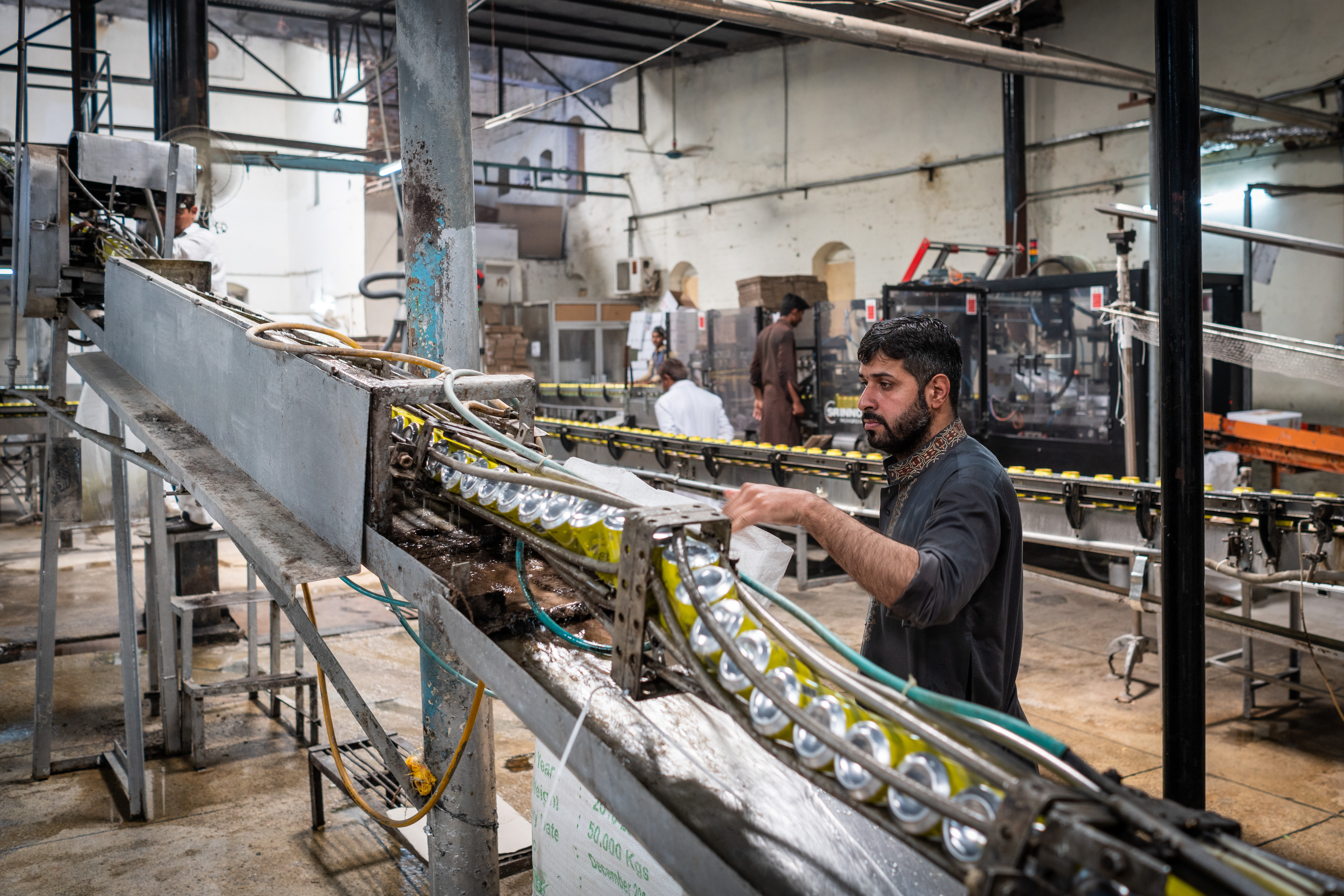 : In einer Halle auf dem Gelände der Murree-Brauerei kontrolliert ein Arbeiter Getränkedosen, die gewaschen werden, bevor sie mit alkoholischen und alkoholfreien Getränken abgefüllt werden; Foto: Philipp Breu